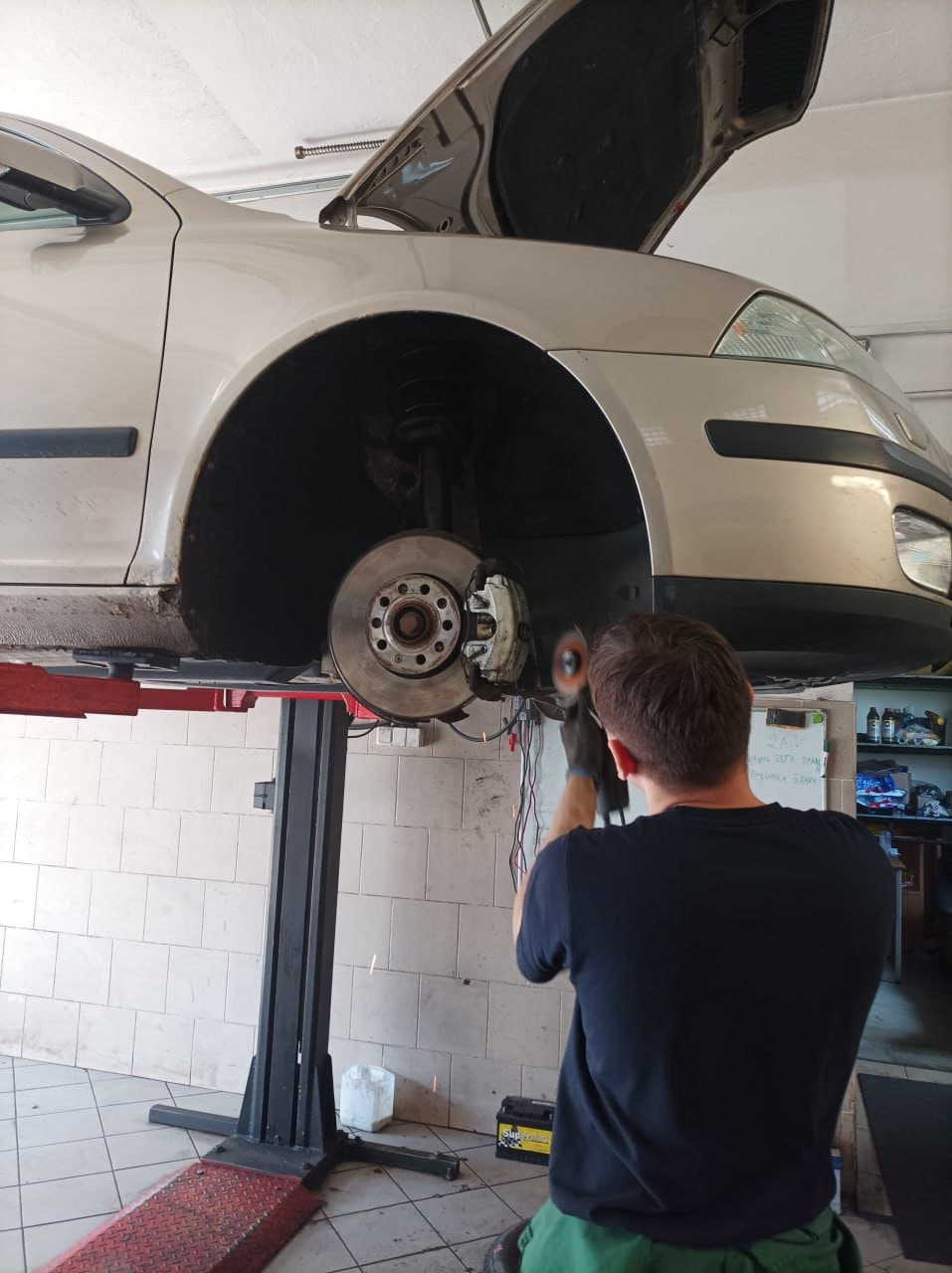 Technik pracující na brzdovém kotouči vozidla na zvedáku
