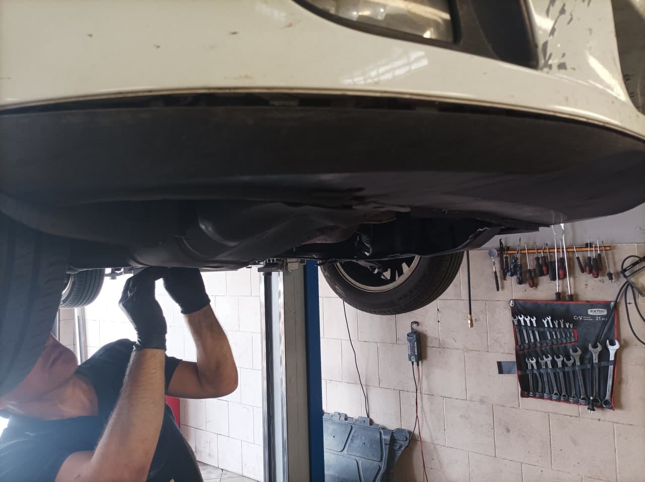 Technik pracující pod vozidlem na zvedáku